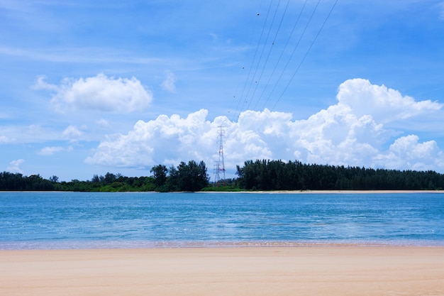 High voltage steel power pylons transmission tower supporting\
high voltage power line tower of power lines in the forest electric\
tower line over sea landscape nature view