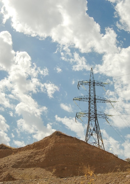 High voltage tower against the blue sky with clouds