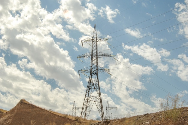 High voltage tower against the blue sky with clouds