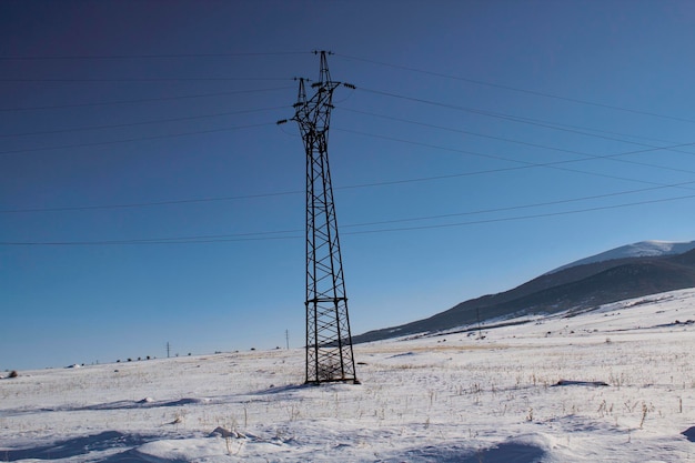 High-voltage tower in winter against the background of the mountain