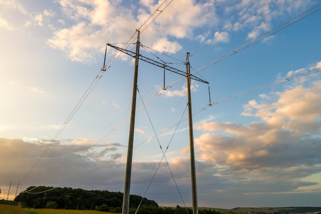 High voltage tower with electric power lines at sunset.