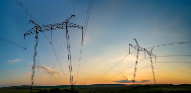 High voltage towers with electric power lines at sunset