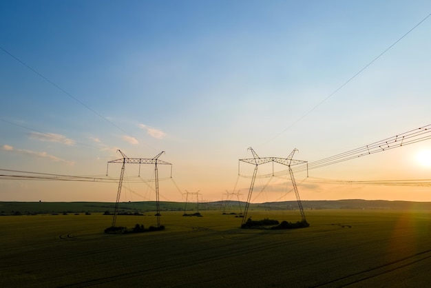 High voltage towers with electric power lines at sunset