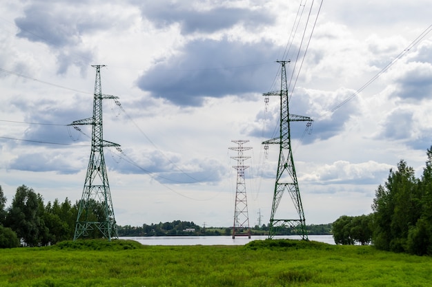 Photo high voltage transmission power tower, electricity pylon stand on the river