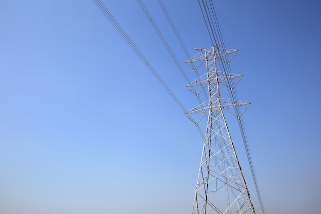 青空の高圧送電塔と電圧配線ケーブル