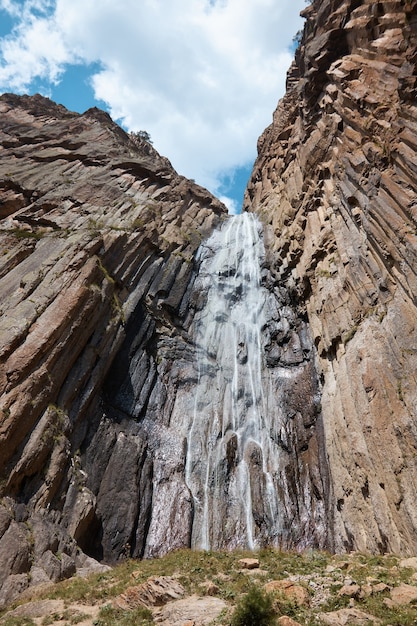 High waterfall, cliff and rocks, bottom view of a mountain waterfall, nature, landscape in the mountains