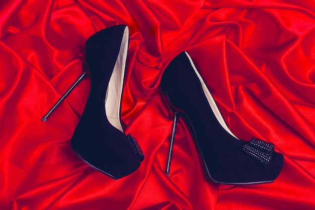 Highheeled shoes lying on red satin