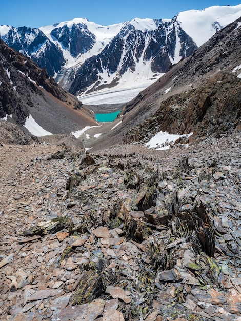 Highland scenery with sharpened stones of unusual shape. Awesome scenic mountain landscape with big cracked pointed stones closeup among snow under blue sky in sunlight. Sharp rocks.