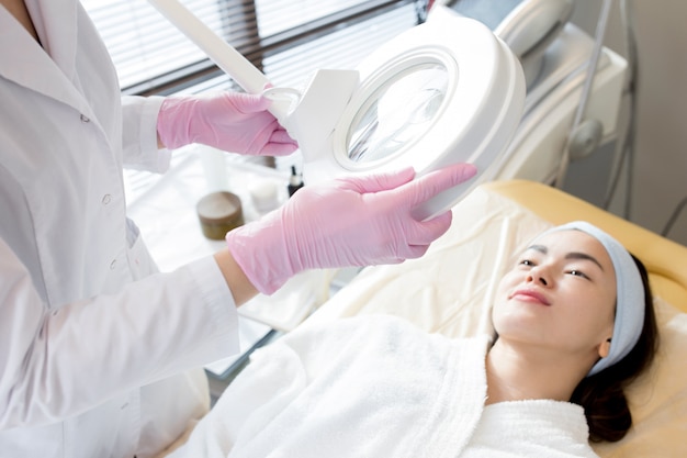 Highly Professional Beautician Using Magnifying Lamp