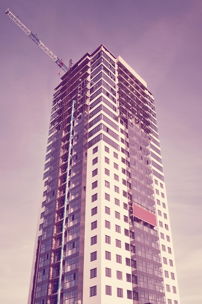 Highrise building under construction with a crane working on the background of the sky