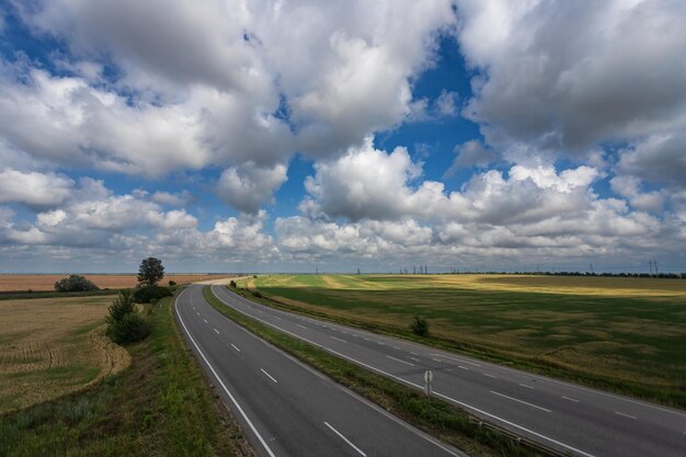 Photo highway among fields under a beautiful sky with white clouds