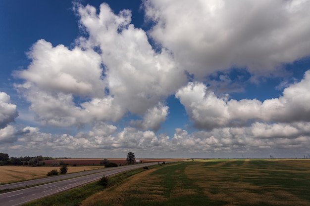 Highway among fields under a beautiful sky with white clouds