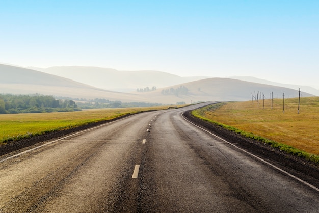 Foto autostrada che si estende in lontananza tra le colline al mattino presto la foto è stata scattata in russia