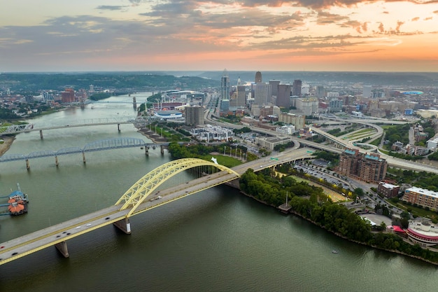 Photo highway traffic in cincinnati ohio on daniel carter beard bridge with brightly illuminated high skyscraper buildings in downtown district american city with business financial district at sunset