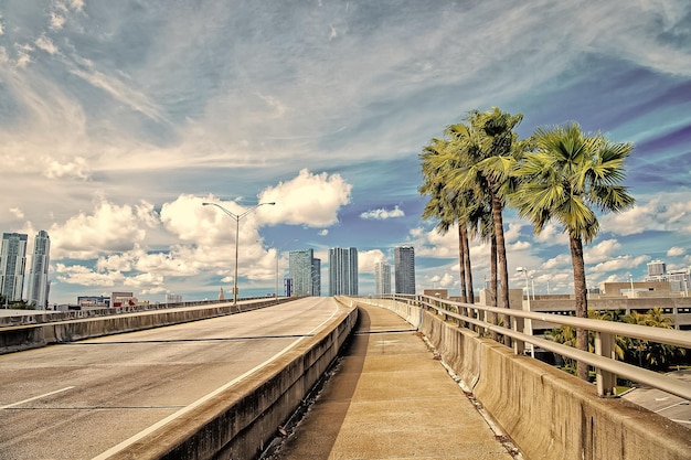 Highway with skyscrapers on blue cloudy sky