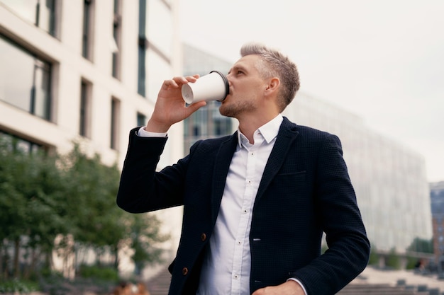 Hij drinkt koffie in een papieren beker in zijn hand Een volwassen mannelijke manager