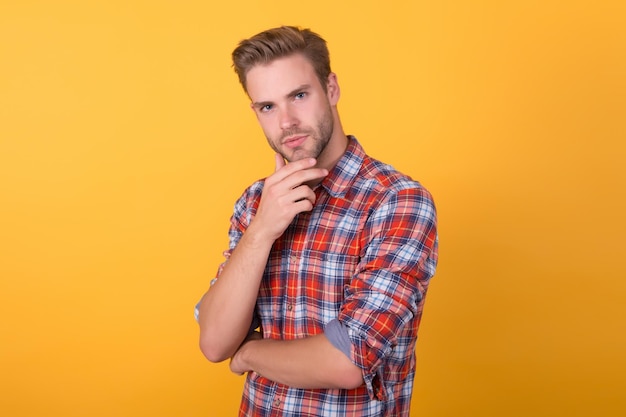 Hij weet beter knappe jongen met haren op gezicht mannelijke schoonheid standaard mannequin op gele achtergrond sexy ongeschoren man denim kleding trend kapperszaak salon man in casual geruit hemd