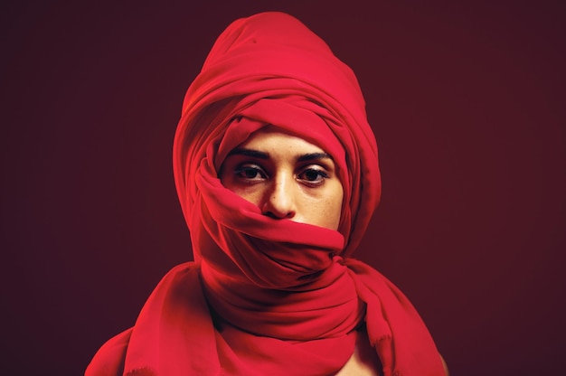 Hijab moslim en portret van een islamitische vrouw in studio met donkere achtergrond Ernstige bedekte en rode Arabische hoofdjurk met een jongere met religieuze cultuur en islam mode sjaal met mockup