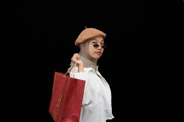 Hijab young girl with shopping bag and expensive glasses on black background