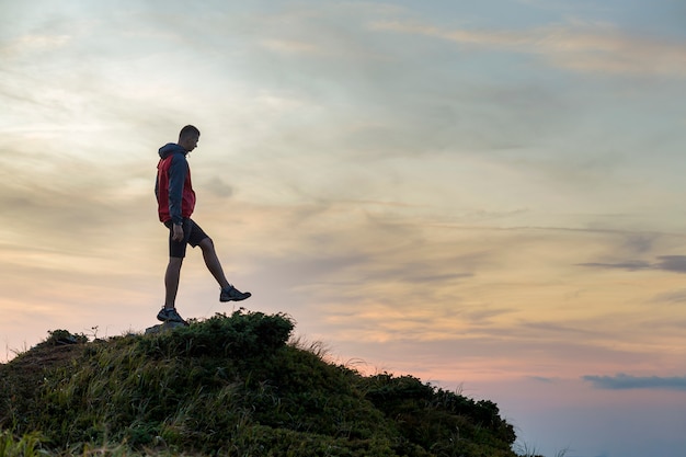 a hiker balancing on a summit stone in mountains