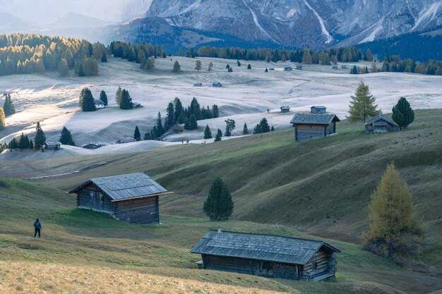 Hiker in beautiful autumnal high alpine pasture with cottages during sunrise dolomites italy