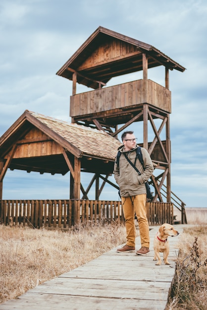 Hiker и собака стоя на деревянной дорожке