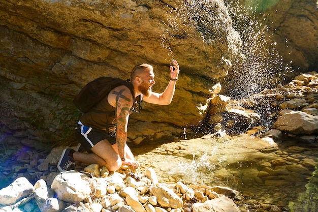 Hiker drinking water from the river man enjoys clean fresh unpolluted water in the mountain creek