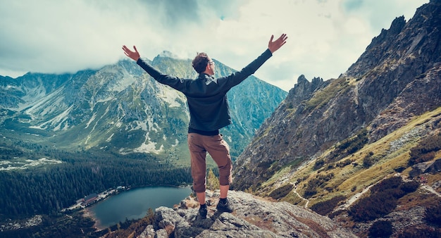 The hiker enjoys the magnificent serene view standing on the edge of the precipice in the tatra