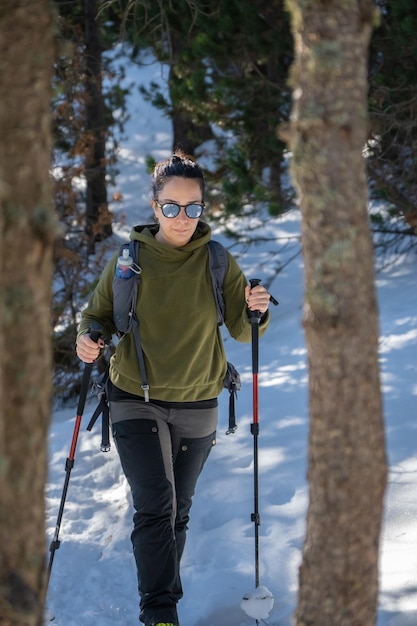 Hiker girl walking through snowy forest of the Spanish Pyrenees