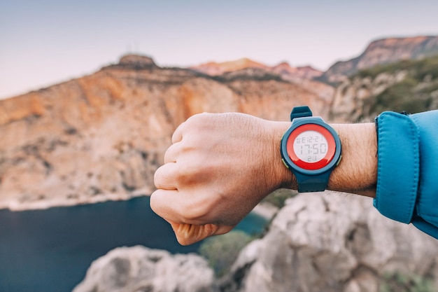Hiker hand with smart wrist watch clocks outdoors