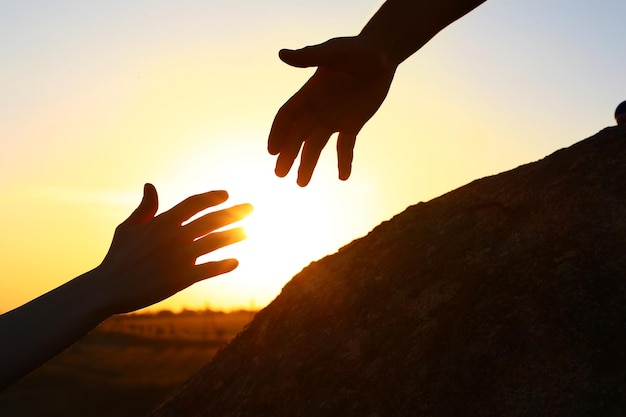 Photo hiker helping friend outdoors at sunset help and support concept