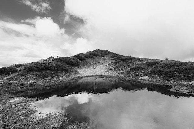 Hiker on hilly bank of river monochrome landscape photo