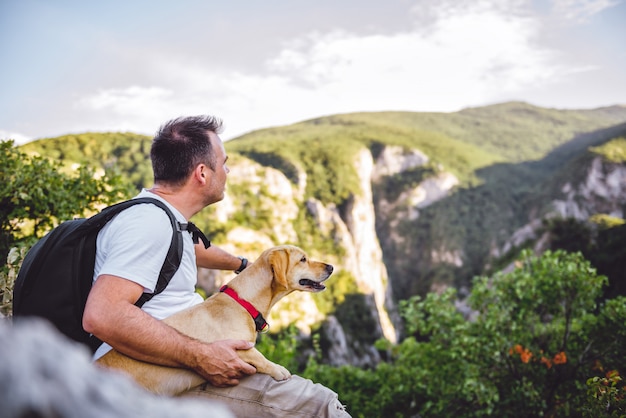 ハイカーと山の上に座っている彼の犬