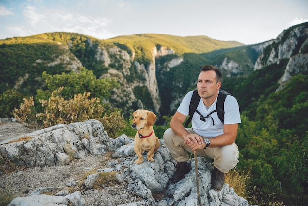 ハイカーと山の上に座っている彼の犬