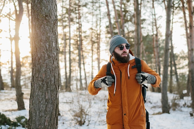 Hiker male walking with backpack in snowy winter forest