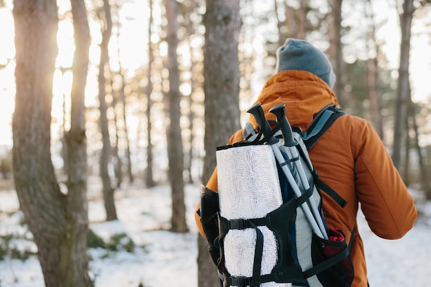 Hiker male walking with backpack in snowy winter forest