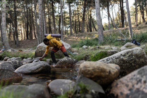 hiker man happy in the nature take water from the river to drink African man adventurous traveler