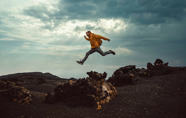 Hiker man jumping over the mountain. Freedom, risk, success and challenge. Focus on man