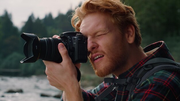 自然の風景の写真を撮るデジタル カメラを持つハイカー男性屋外で働く写真カメラを持つ男性専門家山の川を撮影する若い写真家