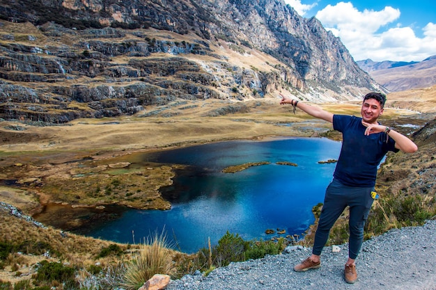 A hiker posing near a lake in the foothills of the snowy Raura Oyon Peru