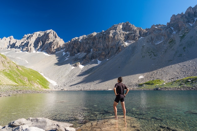 Hiker отдыхая на высоком голубом озере в идиллическом незагрязненном окружении