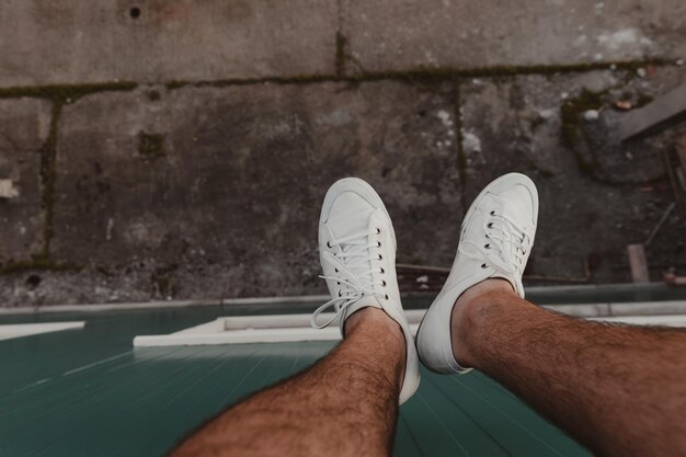 Photo hiker's legs hanging over the edge of a high building