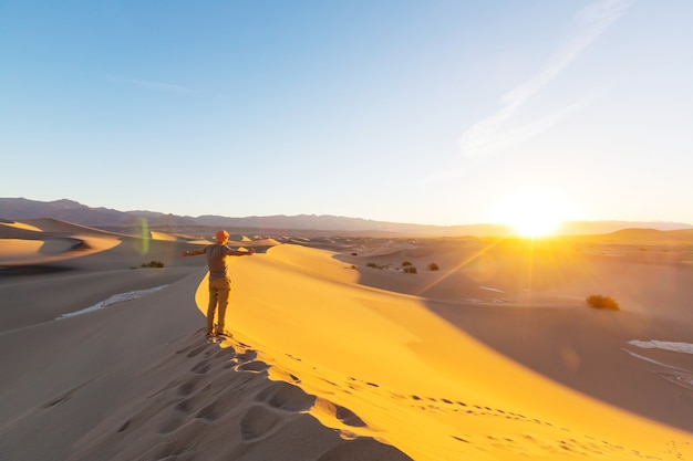 Hiker in sand desert. Sunrise time.