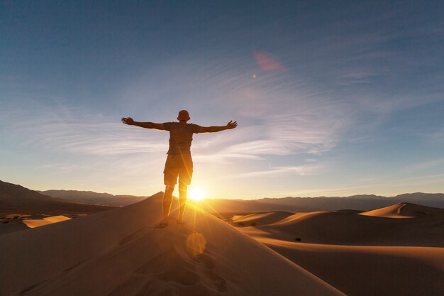 砂砂漠のハイカー。日の出の時間。