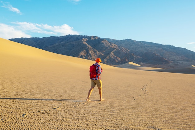 Hiker in sand desert. Sunrise time.