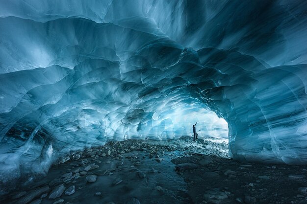 Hiker silhouette exploring an ice cave in the Furgg glacier in Zermatt Wallis Switzerland