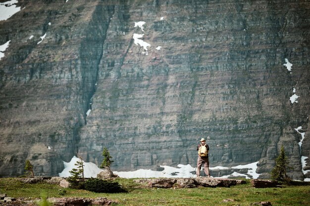 Hiker standing in front of a snowy mountain on a sunny day