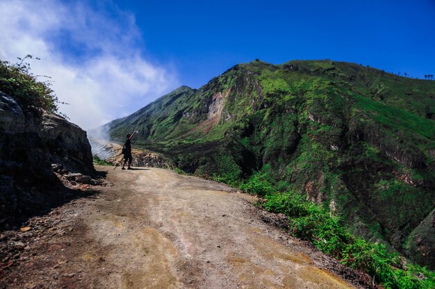 Hiker standing on mountain against blue sky