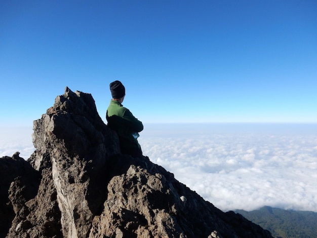 Foto un escursionista in piedi sulla vetta che guarda il paesaggio nuvoloso