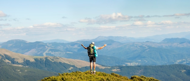 Hiker standing on top of mountain. Unity with nature concept.